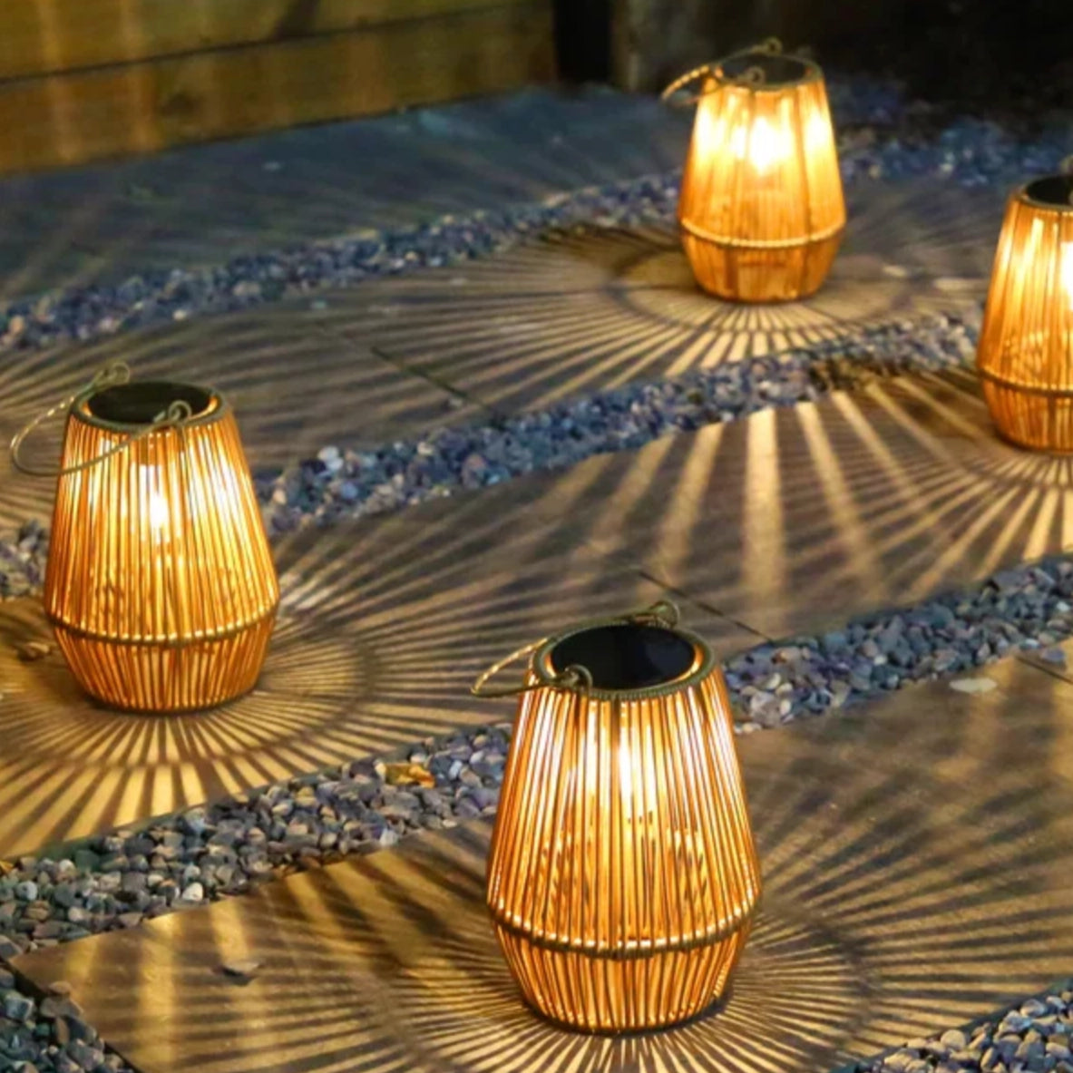 Outdoor garden lit by solar rattan lanterns arranged on stone path