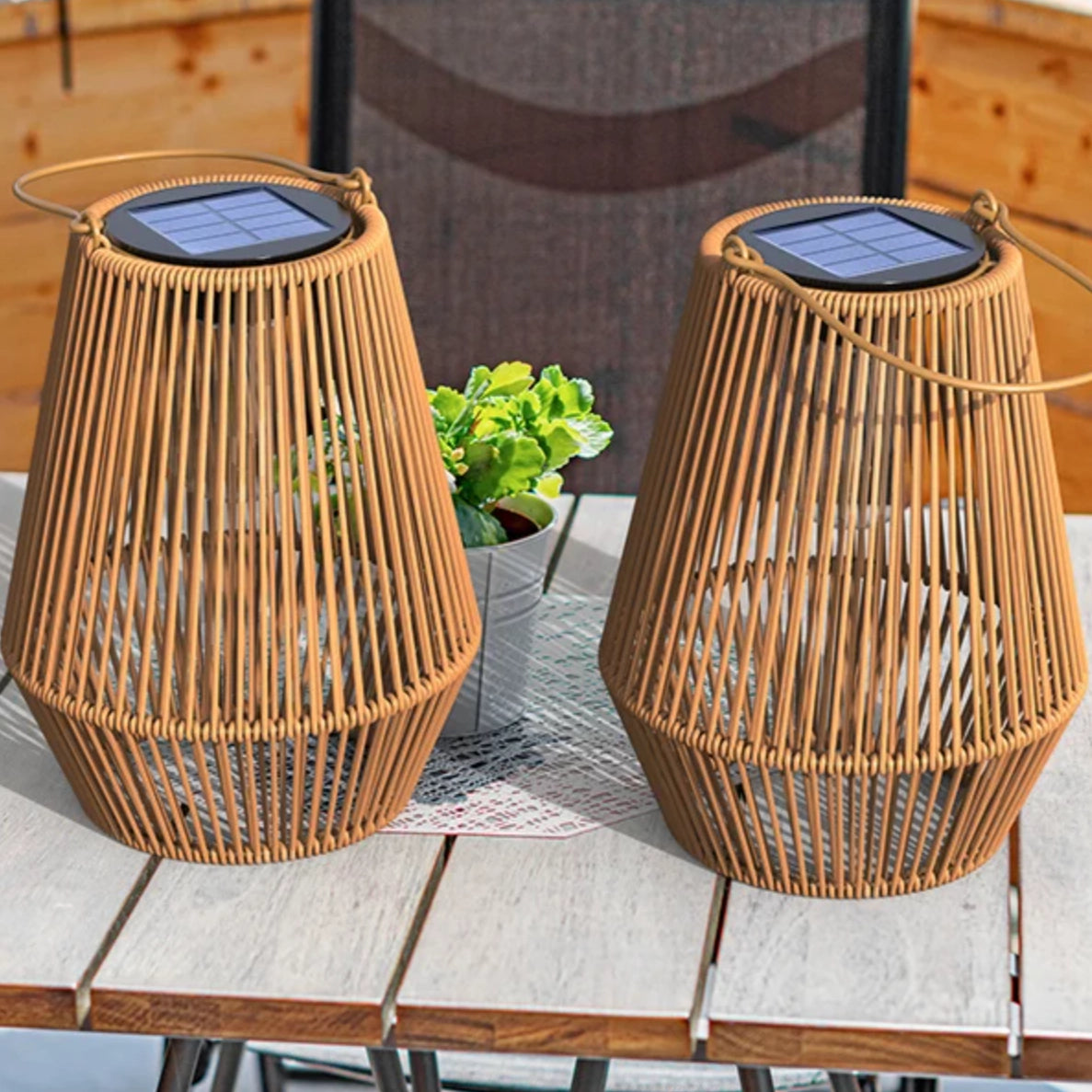 Two woven solar lamps on a table with a plant in the background